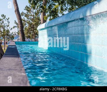 Water in a pool overflowing from the upper one to the bottom one. Crystal clear blue water in an outside pool in croatia Stock Photo