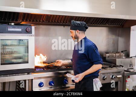 Chef cooking with flame in frying pan Stock Photo