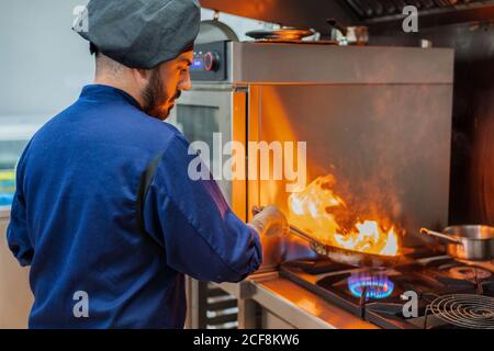 Chef cooking with flame in frying pan Stock Photo