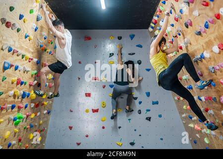 Side view of young group of strong male and female climbers having training on wall in modern gym Stock Photo