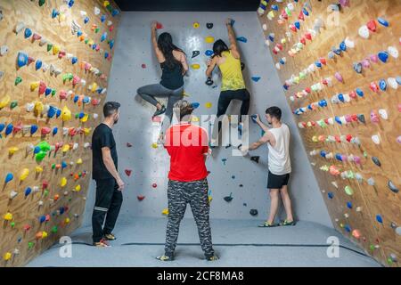 Back view of strong female athlete reflecting in mirror in gym and