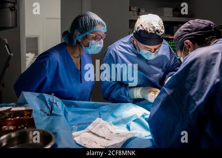 Surgeons and nurses in uniform concentrating and operating patient using special equipment in operating room of contemporary hospital Stock Photo