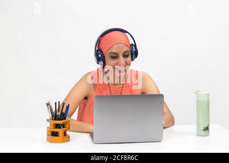 Pretty Indian woman at the table, distance learning for students. Freelancer, distant work, work at home, online education, Listening to music. Stock Photo