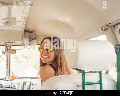 Back view young smiling Woman sitting in front in car looking at camera and man looking from the rearview mirror Stock Photo