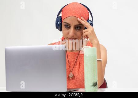 Pretty Indian woman at the table, distance learning for students. Freelancer, distant work, work at home, online education, Listening to music. Stock Photo