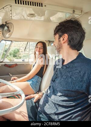 Bearded man and long haired Woman in colorful sunglasses sitting in front sea of car and looking at blue little toy car Stock Photo