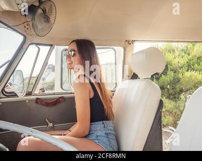Side view of young smiling Woman using sunglasses sitting in front in car Stock Photo
