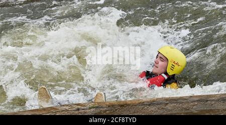 An adolescent boy floats downstream on his back through a stopper at the Nene artificial whitewater course, Northampton, England. Stock Photo
