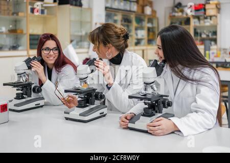 Female scientists using microscopes in lab Stock Photo