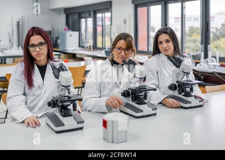 Female scientists using microscopes in lab Stock Photo