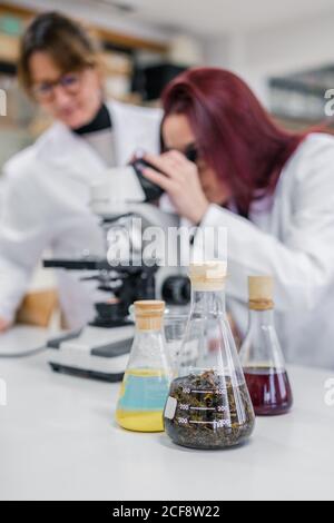 Woman using microscope near colleagues in laboratory Stock Photo