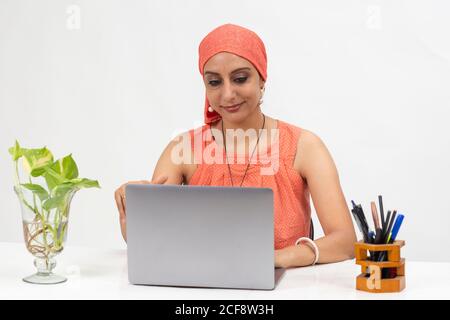 Smiling Indian woman at the table, distance learning for students. Freelancer, distant work, work at home, online education. Stock Photo