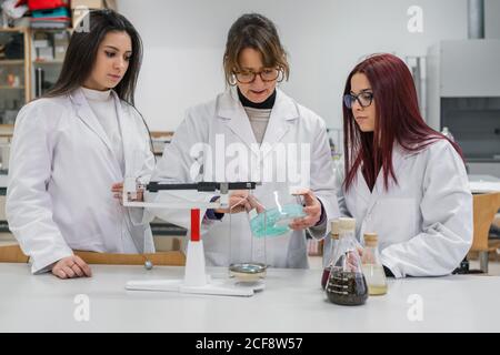 Female teacher and students conducting chemical experiment Stock Photo