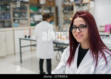 Happy young Woman with red hair smiling and looking at camera while working on scientific research in laboratory in modern university Stock Photo
