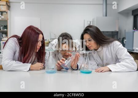 Female teacher and students conducting chemical experiment Stock Photo