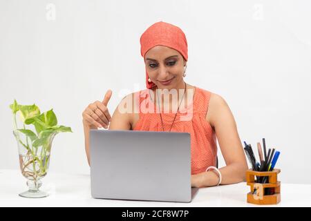 Smiling Indian woman at the table, distance learning for students. Freelancer, distant work, work at home, online education. Stock Photo