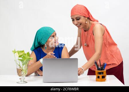 Two smiling Indian women at the table, distance learning for students. Freelancer, distant work, work at home, online education, Discussing project. Stock Photo