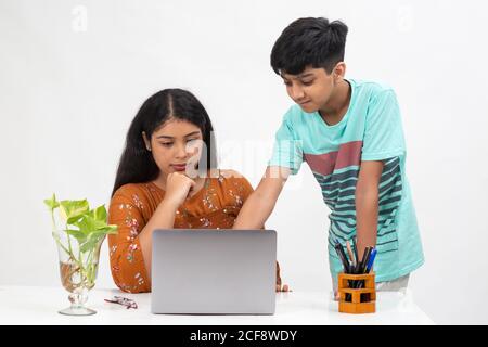 A boy points to a laptop as the girl sits on a table, distance learning for students, study from home, online education, Discussing project. Stock Photo