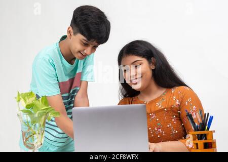 A boy points to a laptop as the girl sits on a table, distance learning for students, study from home, online education, Discussing project. Stock Photo