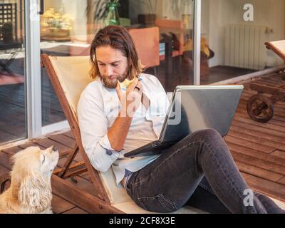 man with laptop giving apple core to dog Stock Photo