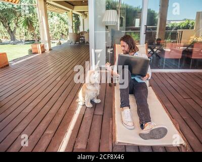 man with laptop giving apple core to dog Stock Photo