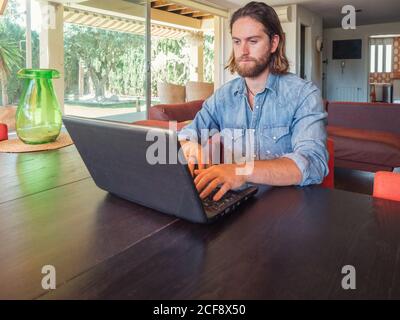 Focused man using computer in apartment Stock Photo