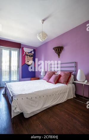 Comfortable steal bed on bright purple wall in modern studio apartment decorated in minimalist style Stock Photo