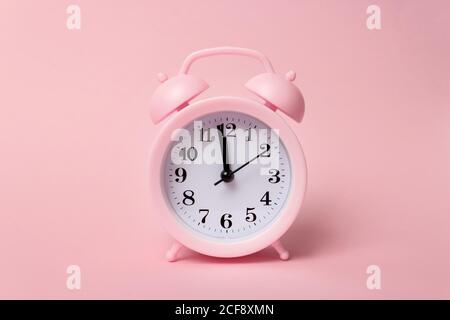 Pastel pink alarm clocks on pink backdrop. Time concept. Minimal composition. Close-Up Of Alarm Clock On Table Against Pink Wall Stock Photo