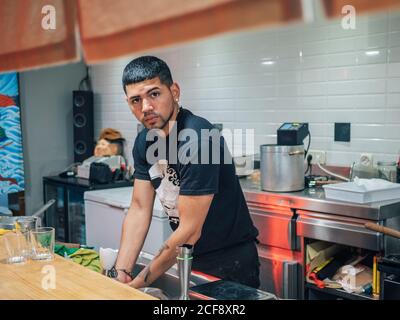 Handsome ethnic young man washing hands while working in Japanese restaurant and cooking ramen Stock Photo