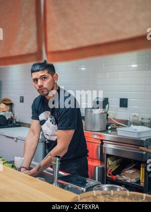 Handsome ethnic young man washing hands while working in Japanese restaurant and cooking ramen Stock Photo