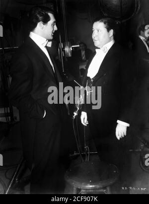 CARY GRANT and JACK OAKIE on set candid during filming of THE TOAST OF NEW YORK 1937 director ROWLAND V. LEE RKO Radio Pictures Stock Photo