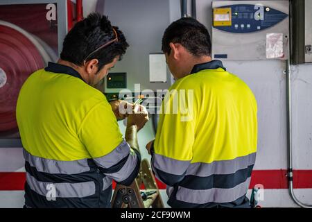 Back view of group of professional male technicians with electric tools repairing and checking equipment while working in building Stock Photo