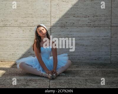 Ballerina sitting on floor stretching graceful in classroom Stock Photo