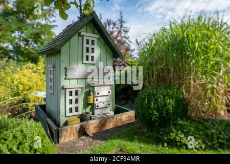 tall green birdhouse on a tree hanging in garden Stock Photo