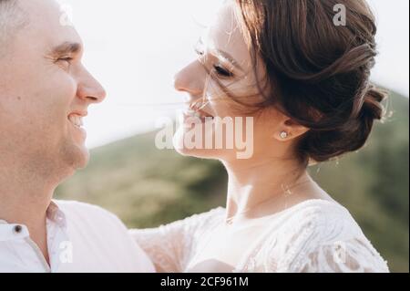 Beautiful fabulous happy bride and stylish groom posing on the background of the sunny stunning mountains. Stock Photo