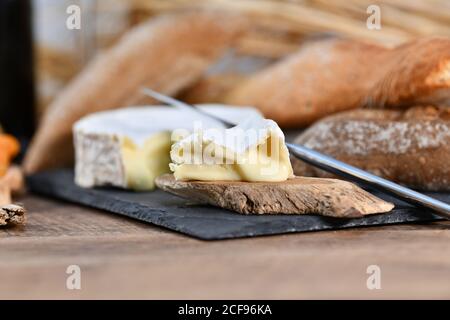 Delightful various types of white cheese and crispy fresh bread with pieces of wood on rustic table Stock Photo