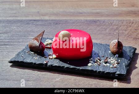 Slate board with served dessert of delicious vanilla mouse with raspberry and white chocolate in sunlight Stock Photo