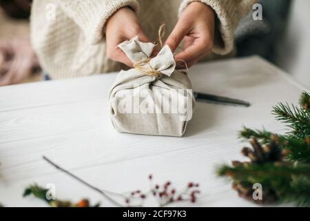 Stylish christmas gift wrapped in fabric on rustic table with