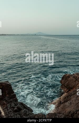 top view of sea waves hitting rocks on the beach with turquoise blue ...