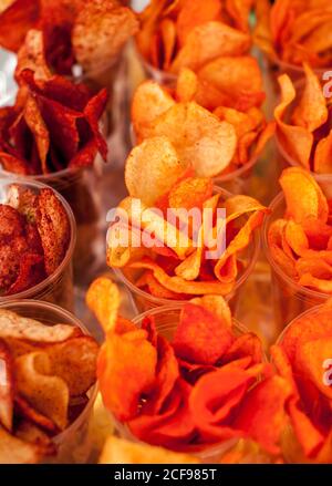 From above food background with various tasty savory crispy chips served in small plastic cups Stock Photo