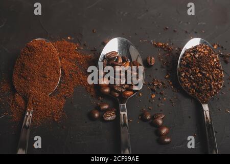 Types of coffee grounds instant and powder and coffee beans in spoons on black table Stock Photo