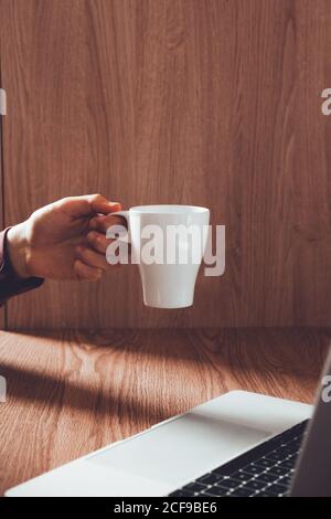 Crop man with mug using laptop Stock Photo