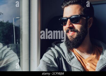 Young bearded man looking through window while traveling by train Stock Photo