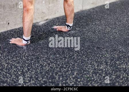 Crop hands of young male doing handstand near grey wall in gym Stock Photo