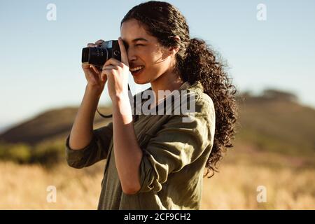 Close up of a woman taking photo using a digital camera. Tourist woman doing nature photography on a sunny day. Stock Photo
