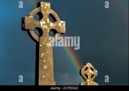 Rainbow over old Celtic cross Irish cemetery Stock Photo