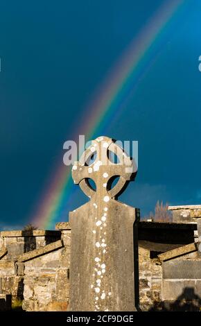 Rainbow over old Celtic cross Irish cemetery Stock Photo