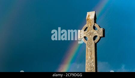 Rainbow over old Celtic cross Irish cemetery Stock Photo