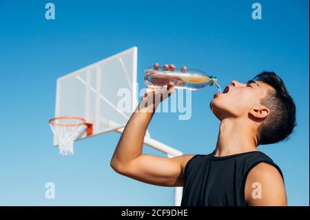Young man playing on basketball court outdoor drinking water Stock Photo