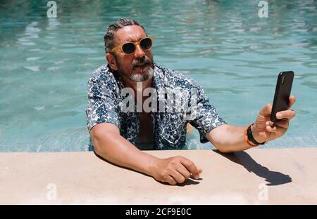 Senior man using smartphone in swimming pool Stock Photo